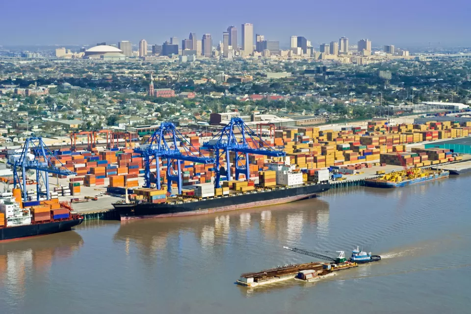 Aerial view of New Orleans port with cranes and barges and skyline in background